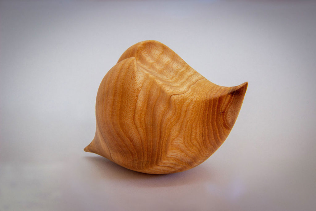 Side view of the "Love seed" sculpture (sensory and ergonomic sculpture in the hand, inspired by the shape of the heart, in ash) - Original creation by Coralie Saramago