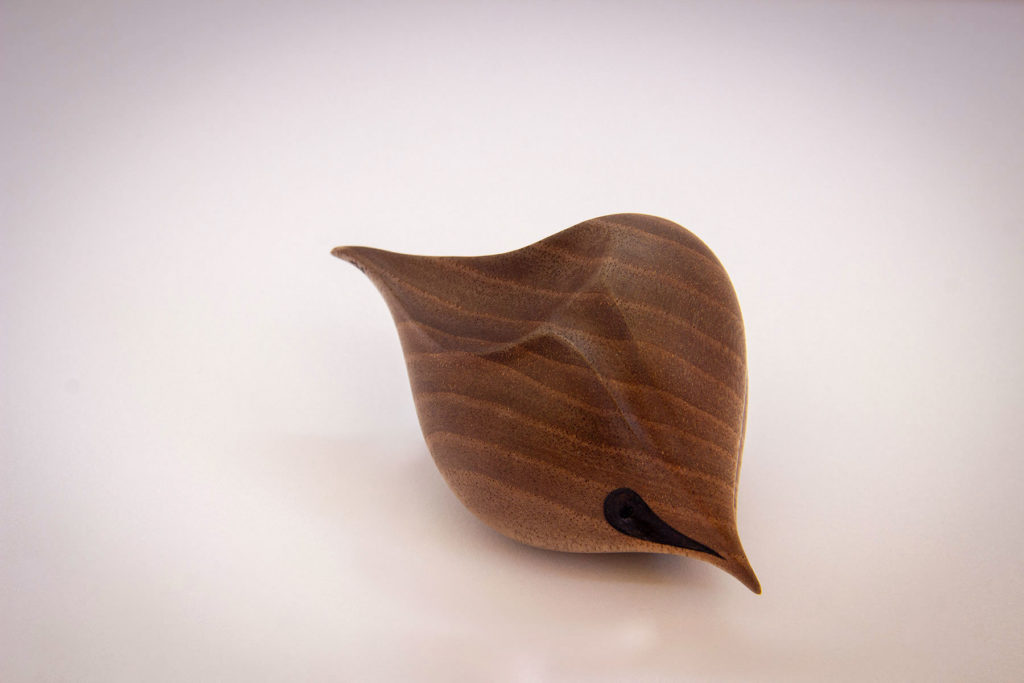 Side view of the turned sculpture: "Birdy love seed" (sensory and ergonomic sculpture in the hand, inspired by the shape of the heart, in dark walnut) - Original creation by Coralie Saramago