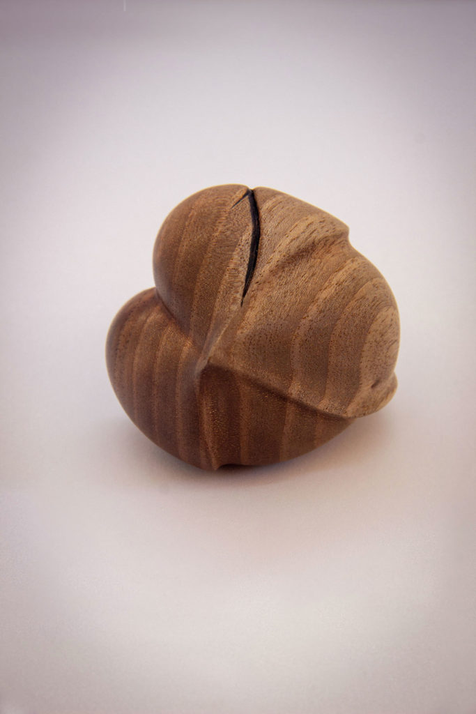 Bottom view of the turned sculpture: "Corsage love seed" (sensory and ergonomic sculpture in the hand, inspired by the shape of the heart, in dark walnut) - Original creation by Coralie Saramago