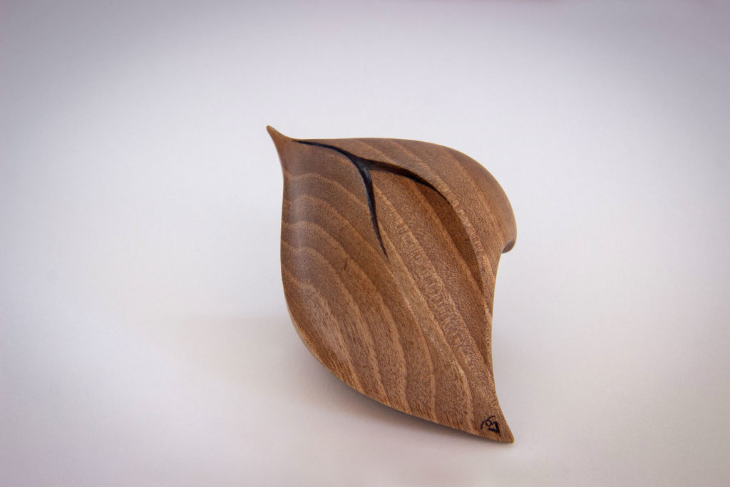 Side view of the "love seed" sculpture (sensory and ergonomic sculpture in the hand, inspired by the shape of the heart, in dark walnut) - Original creation by Coralie Saramago